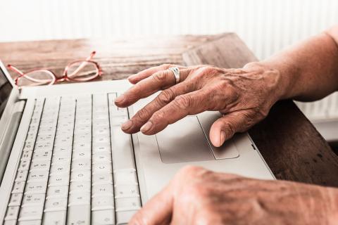an older person's hands using a laptop