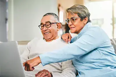 An older man and woman using a laptop together