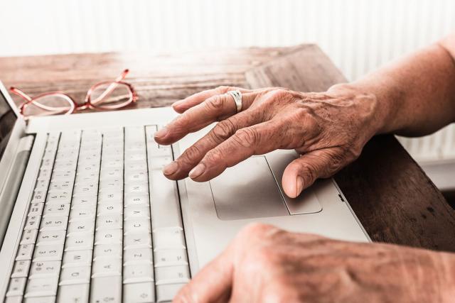 an older person's hands using a laptop
